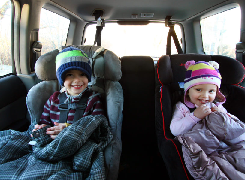 child in car seats with coats on their laps